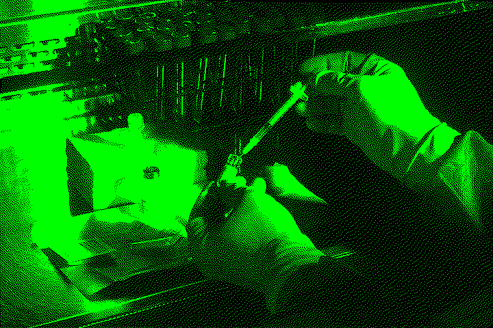 A person wearing blue gloves preparing a syringe with liquid from a vial in a laboratory setting.